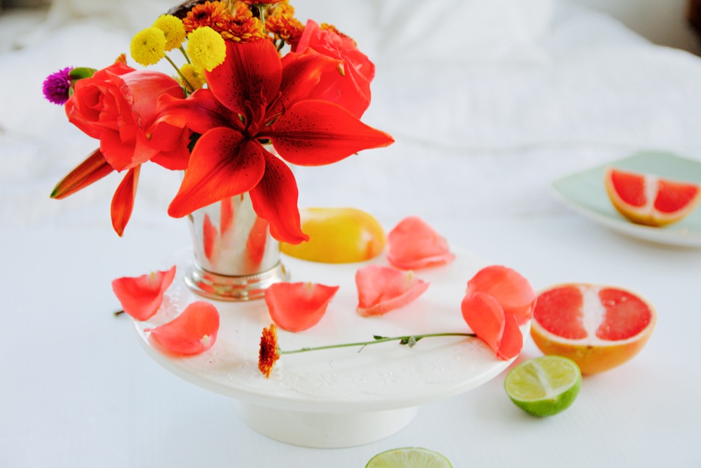 A silver cup of pink, red and yellow flowers on a white background