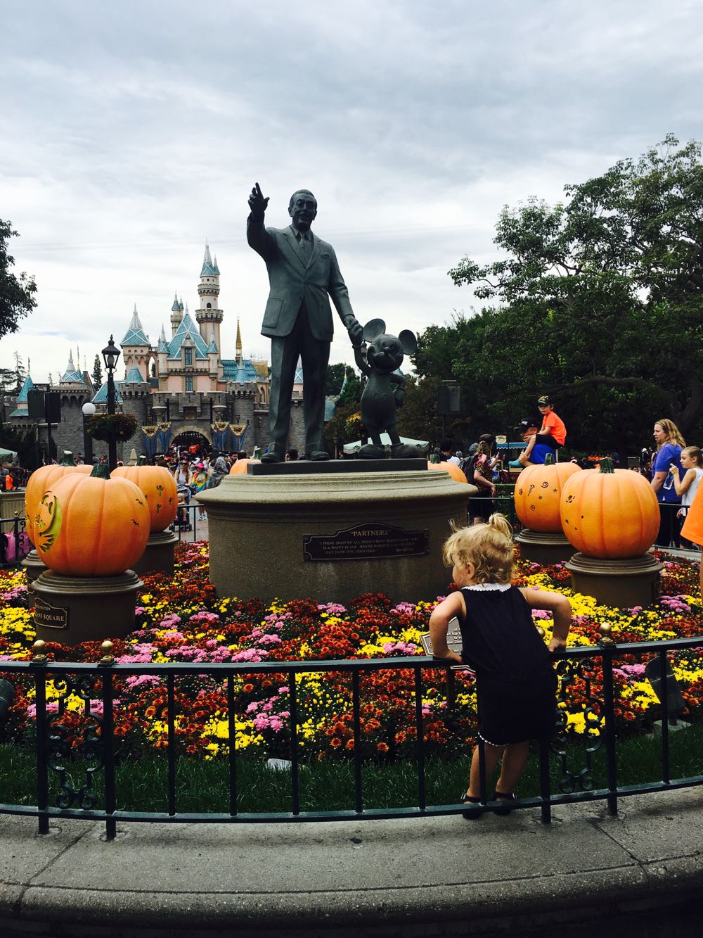 standing in front of the walt disney statue at disneyland